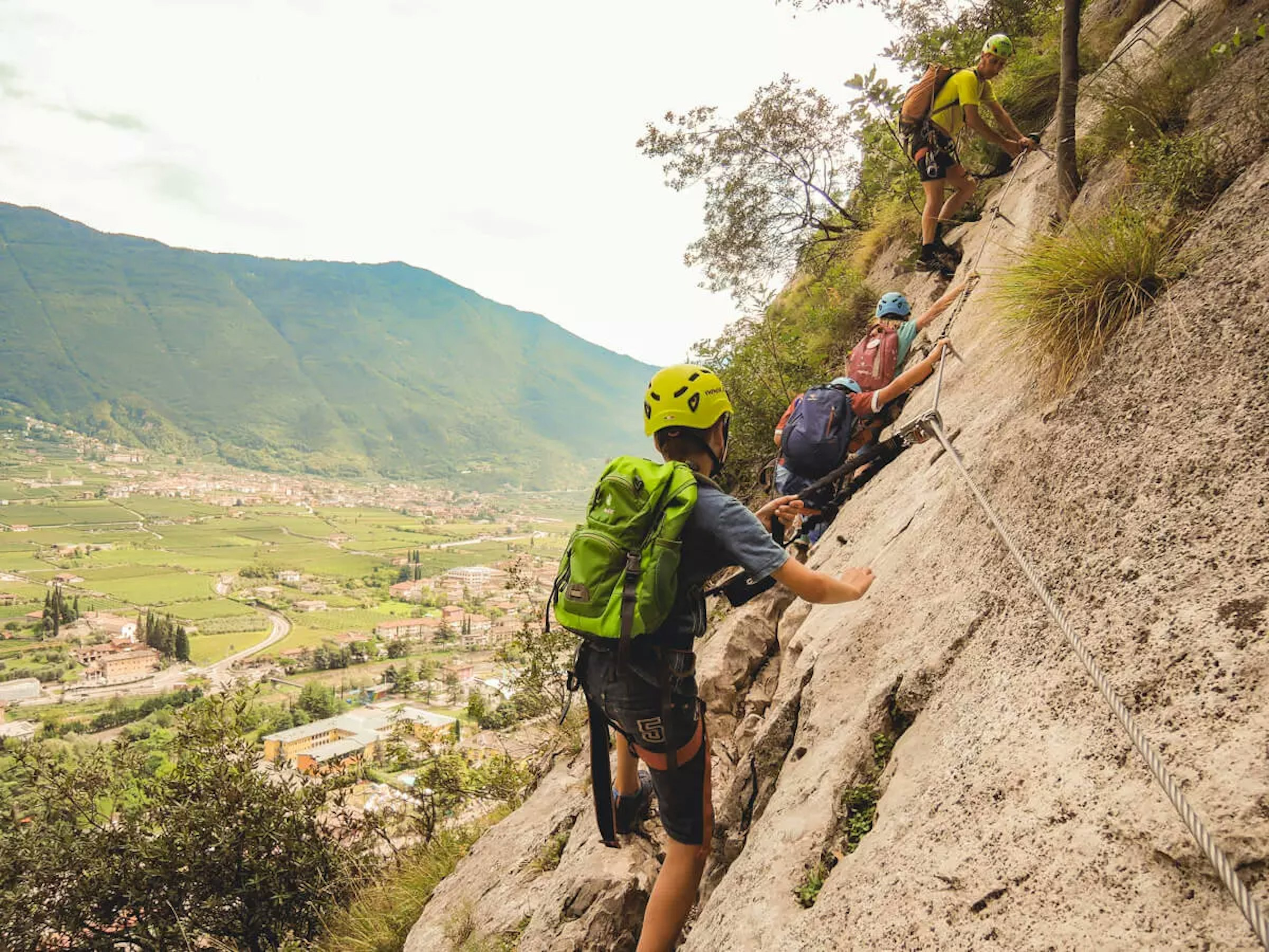 Vier Kinder die gesichert an einer Felswand klettern mit Ausrüstung