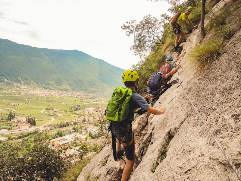 Vier Kinder die gesichert an einer Felswand klettern mit Ausrüstung