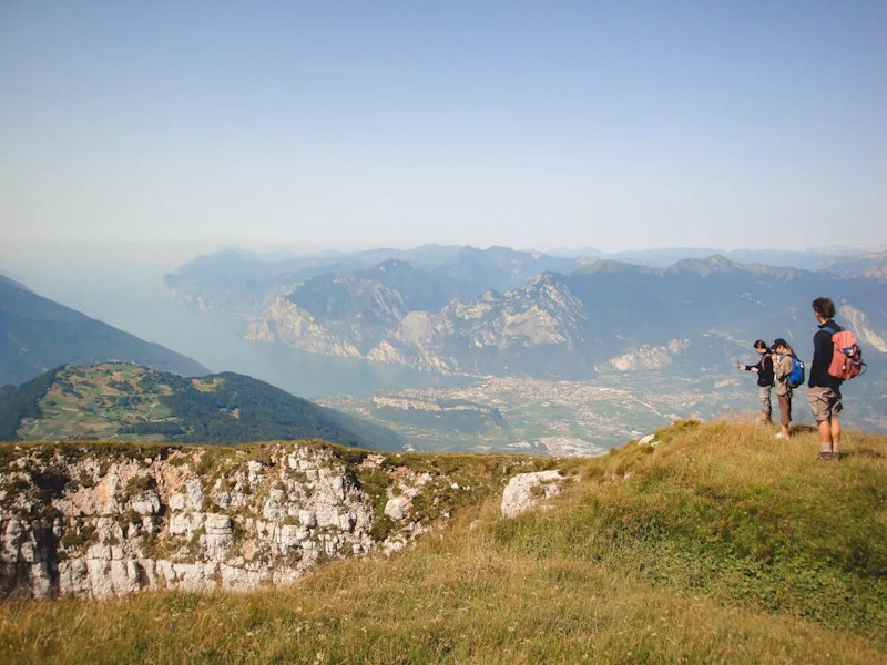 Drei Menschen stehen auf einem Berg und schauen ins Tal