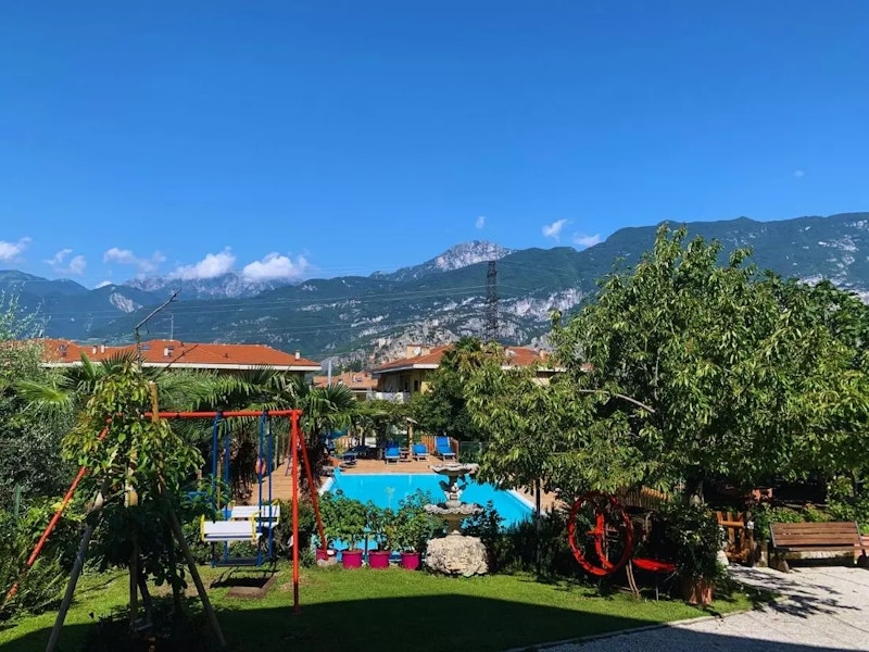 Blick auf die Anlage mit Pool, im Hintergrund Berge und blauer Himmel