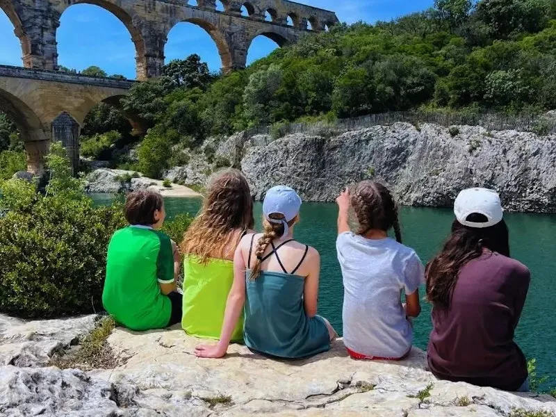 Kinder von hinten auf einem Stein an einem See