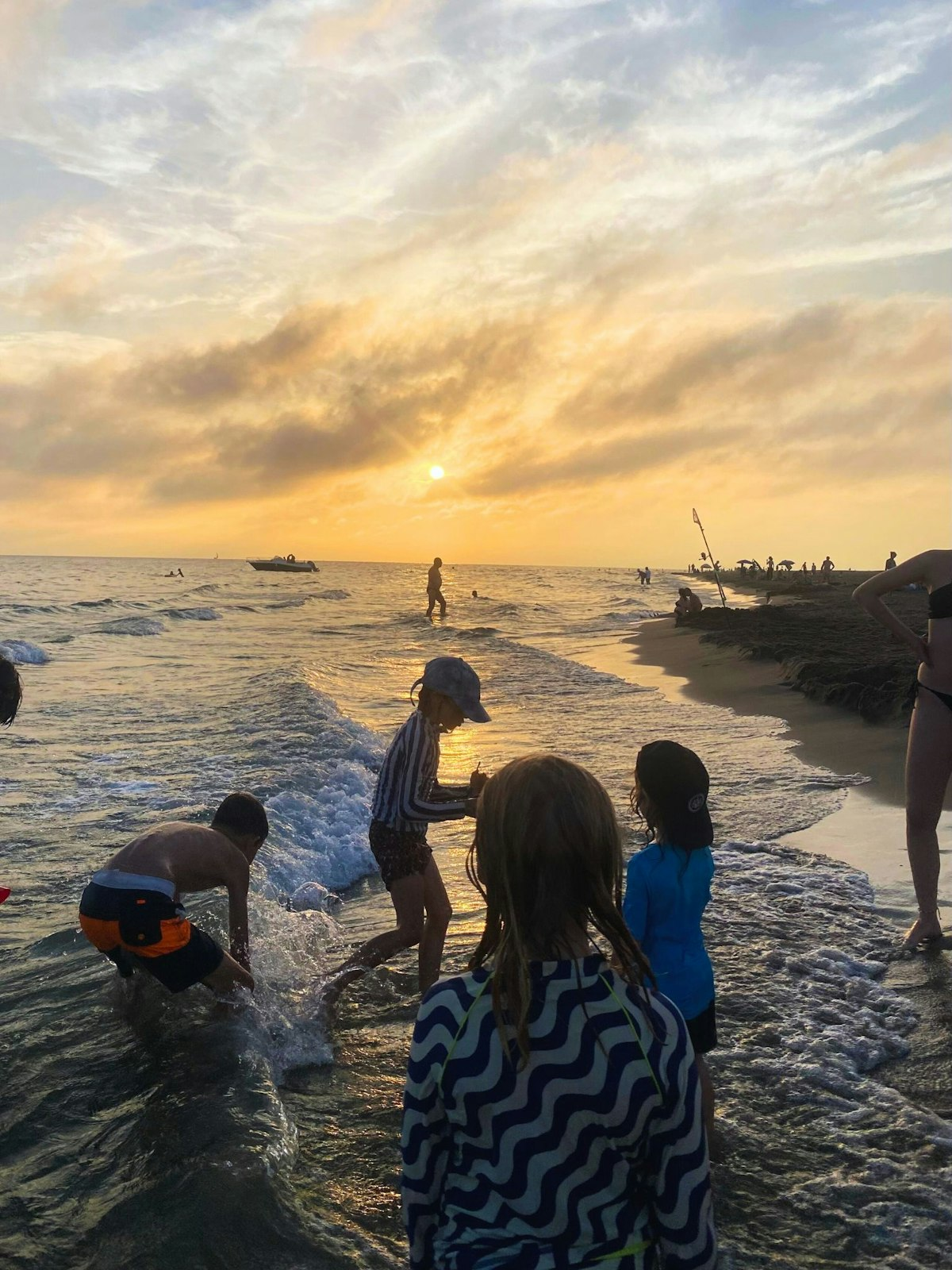 Eine Gruppe Kinder spielt am Strand bei Sonnenuntergang