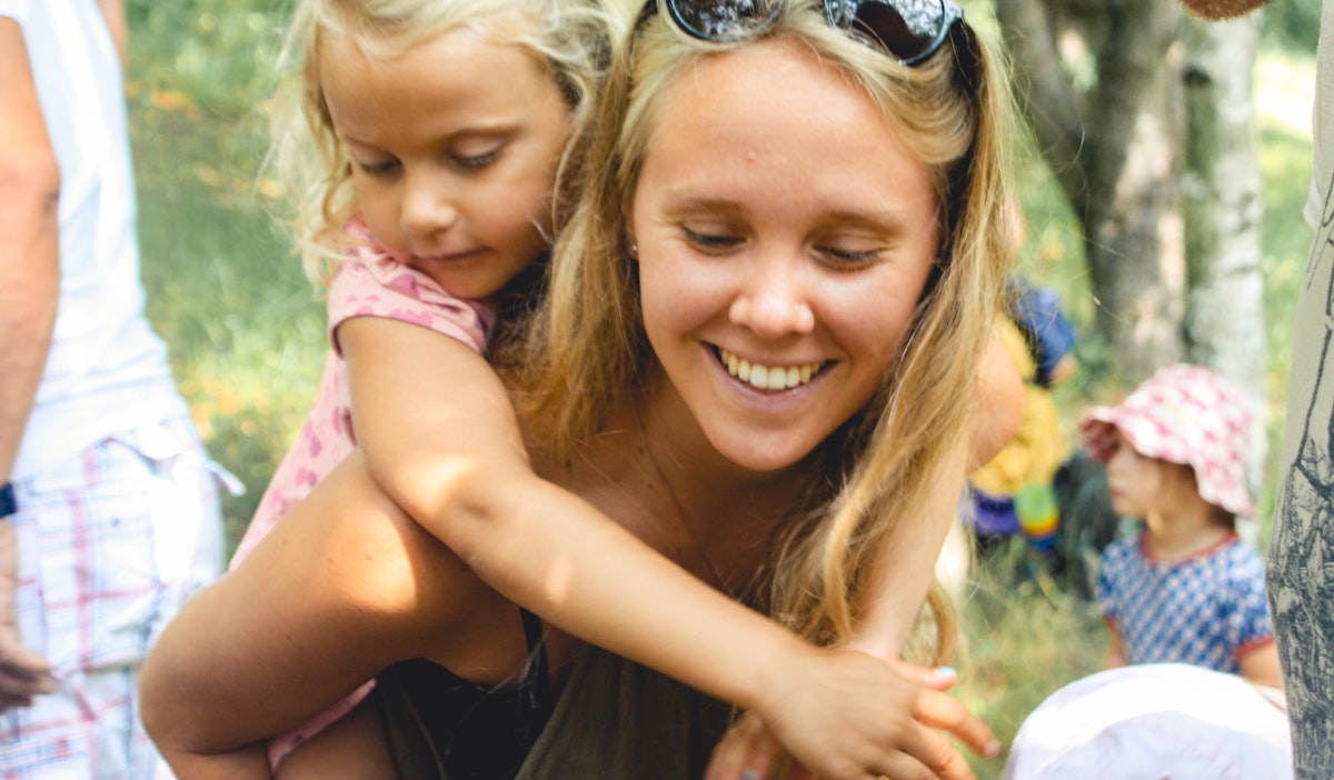 Eine junge Frau die ein Mädchen auf dem Rücken trägt