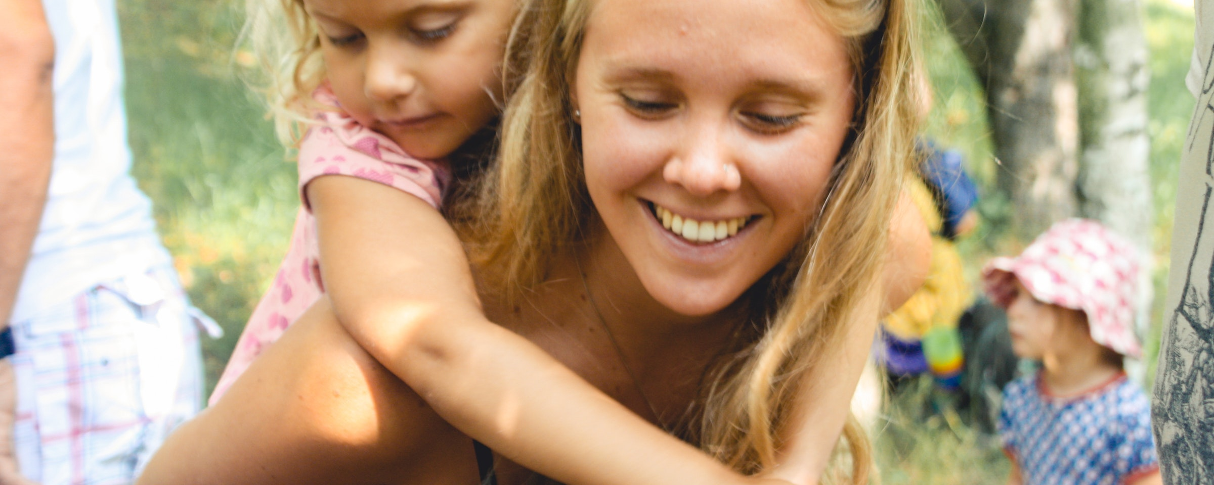 Eine junge Frau die ein Mädchen auf dem Rücken trägt
