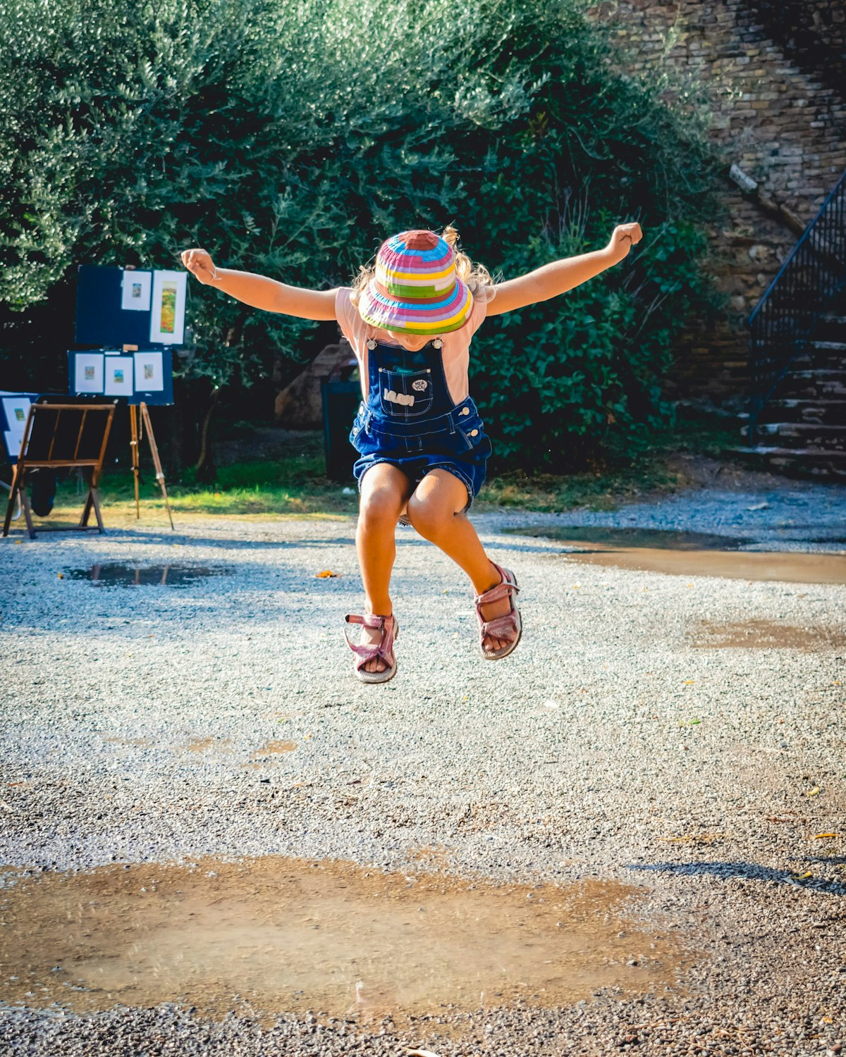 Ein kleines Mädchen mit Hut springt in eine Pfütze