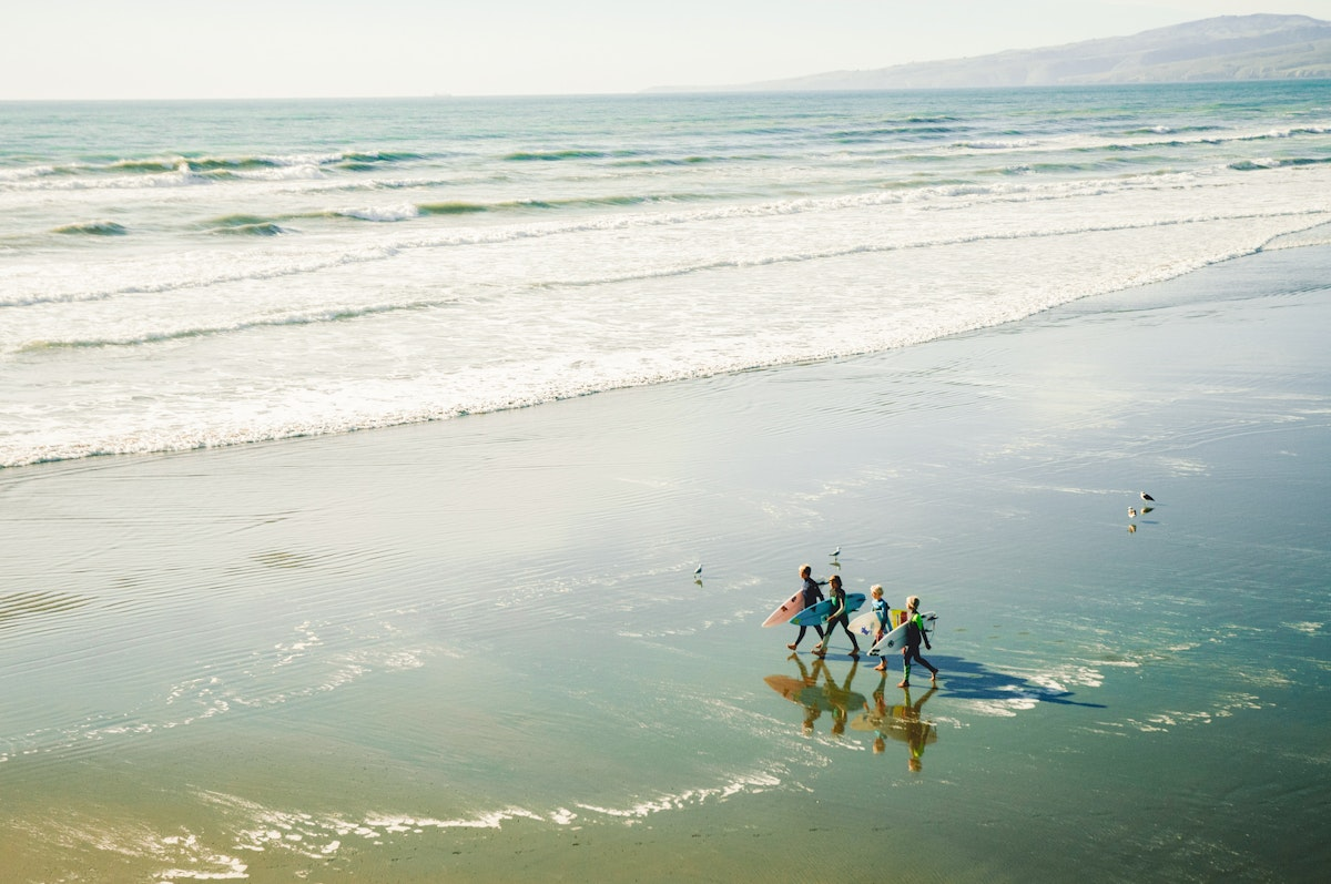 Eine Gruppe Surfer am Strand aus der Luft fotografiert
