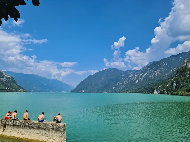 ein türkisblauer See mit einer Gruppe Schwimmern auf einer Mauer