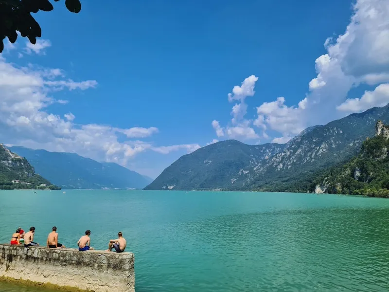 ein türkisblauer See mit einer Gruppe Schwimmern auf einer Mauer
